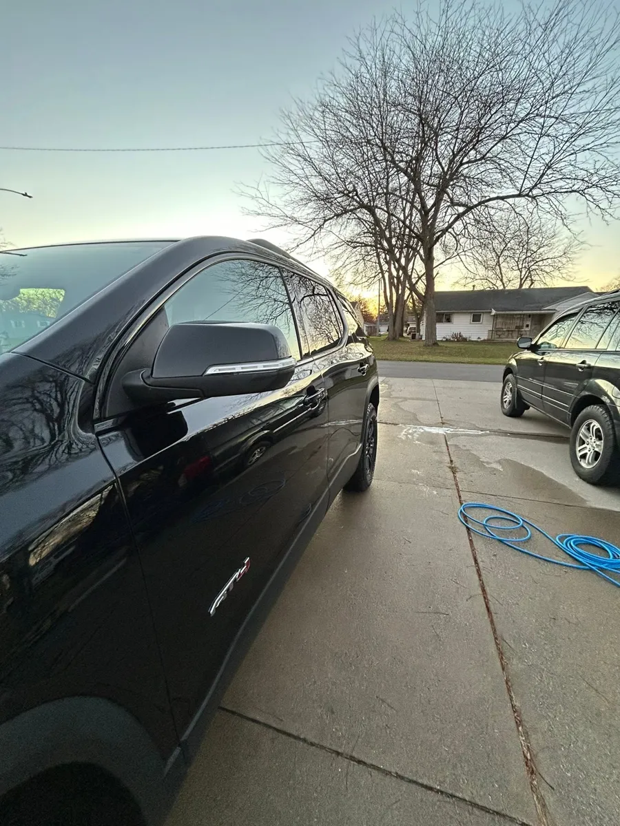Black GMC Acadia rear quarter after a wash